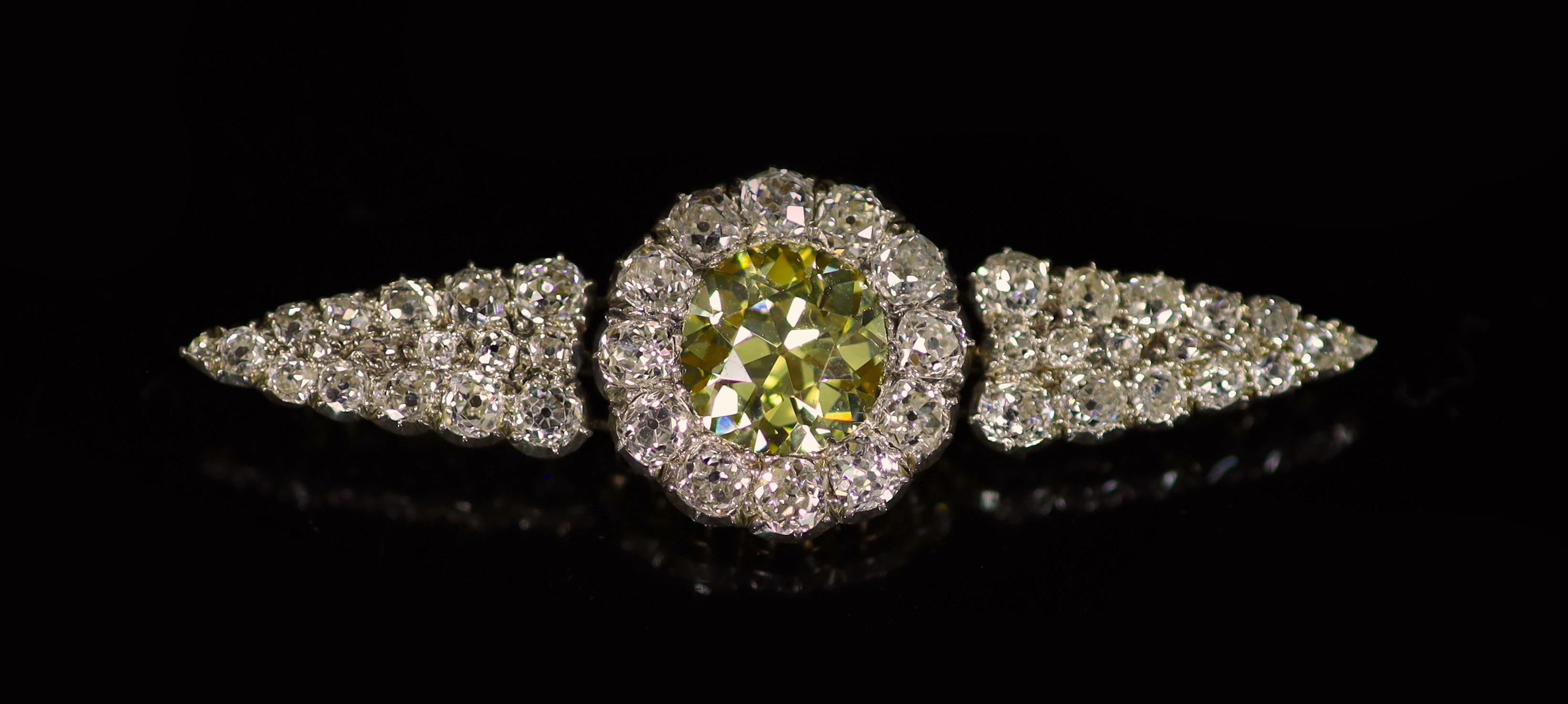 A good early 20th century gold and silver, single stone fancy yellow diamond and old mine cut white diamond set cluster brooch